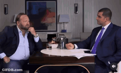 Two Men In Suits Talking At Table GIF