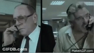 Two Men In Suits Talking On Phones GIF