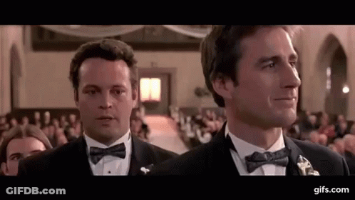 Two Men In Tuxedos And Bow Ties Are Standing Next To Each Other In A Church . GIF