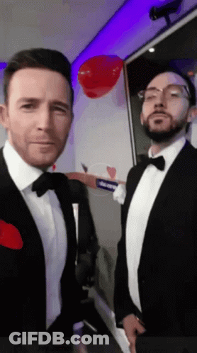 Two Men In Tuxedos And Bow Ties With Red Heart GIF