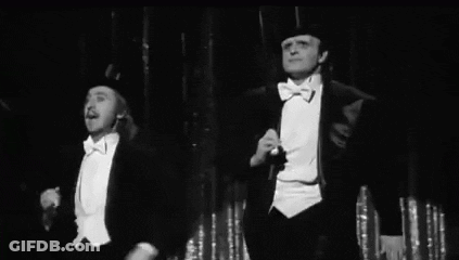 Two Men In Tuxedos And Top Hats On Stage GIF