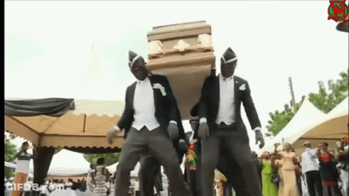 Two Men In Tuxedos Are Carrying A Coffin And Dancing In Front Of A Crowd GIF