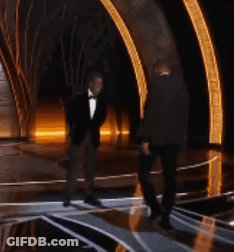 Two Men In Tuxedos Are Dancing On A Stage At An Event GIF