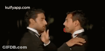 Two Men In Tuxedos Are Hugging Each Other . GIF