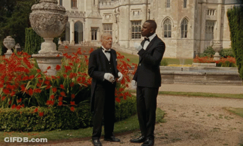 Two Men In Tuxedos Standing In Front Of A Large Building GIF