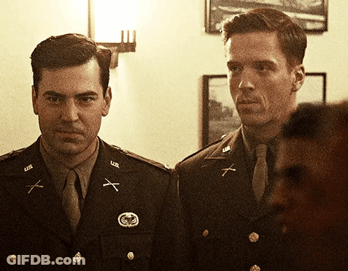 Two Men In U.s. Army Uniforms Are Standing Next To Each Other In A Room GIF