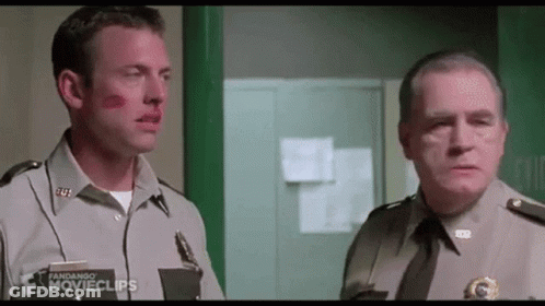 Two Men In Uniform Are Standing Next To Each Other In A Hallway . GIF