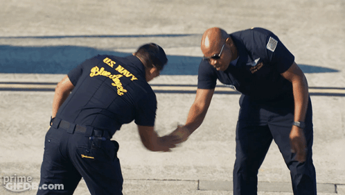 Two Men In Us Navy Uniforms Shake Hands With Each Other GIF