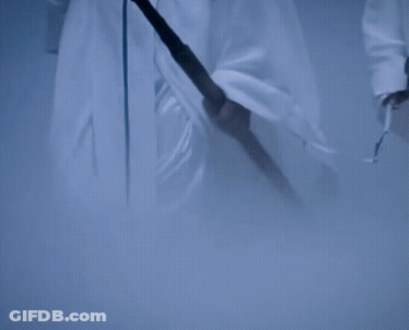 Two Men In White Robes Are Holding Swords And Walking In A Cave GIF