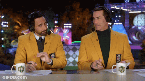 Two Men In Yellow Jackets And Headphones At Table With Golf Channel Cup GIF