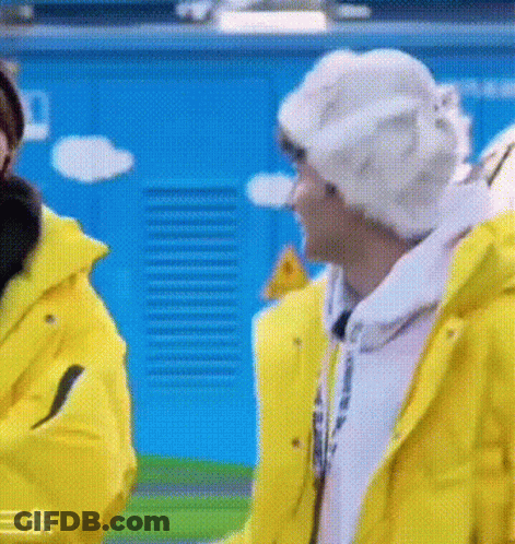 Two Men In Yellow Jackets And White Hats Talking GIF