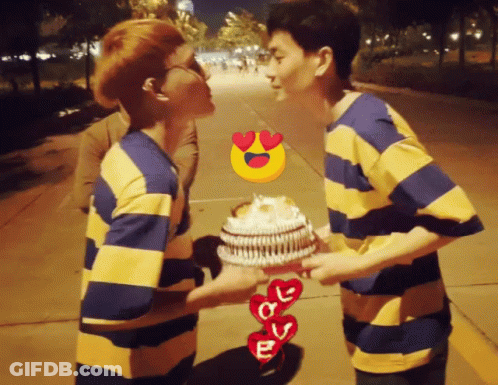Two Men Kissing While Holding A Cake With Hearts And The Letter E GIF