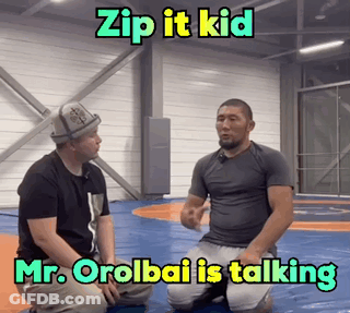 Two Men Kneeling On Wrestling Mat Talking GIF