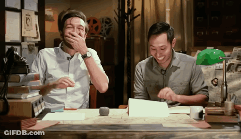 Two Men Laughing At Desk One Covering Mouth GIF