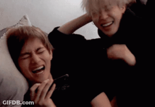 Two Men Laughing On Bed One Holding Phone GIF