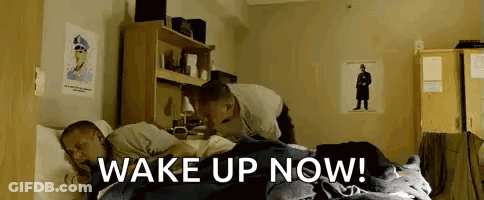 Two Men Laying In Bed Saying Wake Up Now GIF