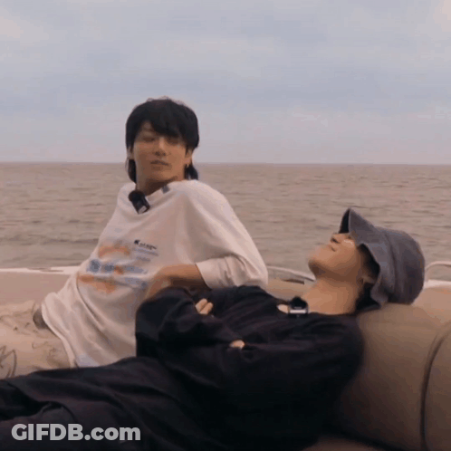 Two Men Laying On A Boat With One Wearing A Shirt That Says ' Abercrombie & Fitch ' GIF