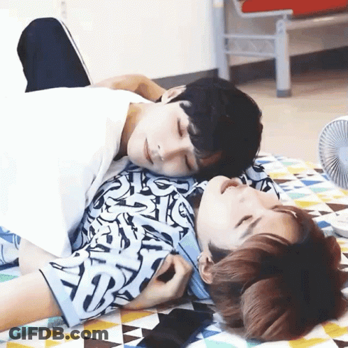 Two Men Laying On Top Of Each Other On Blanket With Fan GIF