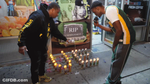 Two Men Lighting Candles At RIP Sign GIF