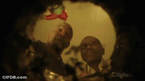 Two Men Looking Through Hole In Wall Saying Citytv GIF