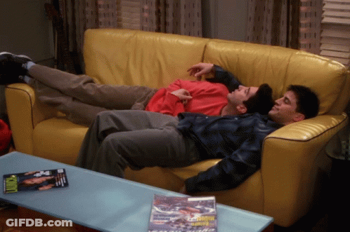 Two Men Lying On Yellow Couch With Motorcycle Magazine GIF