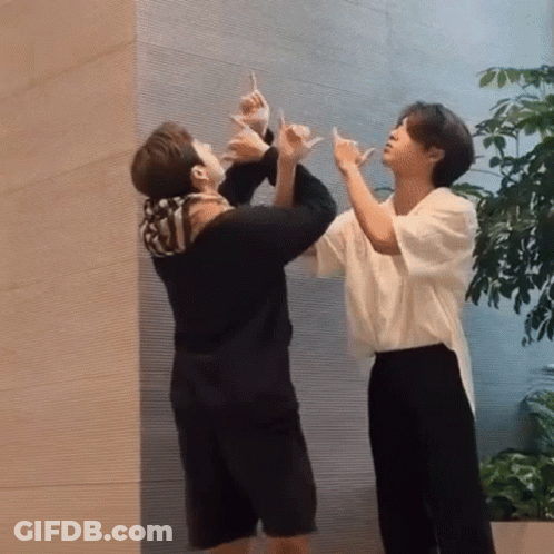 Two Men Making Hand Signs In Front Of Wall GIF