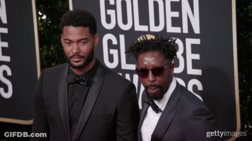 Two Men On A Red Carpet With A Sign That Says Golden Globe On It GIF