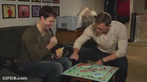 Two Men On Couch One Holding Green Box Saying A GIF