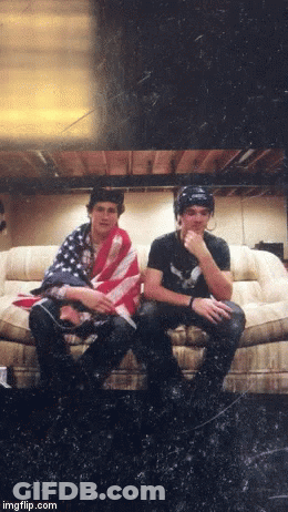 Two Men On Couch One With American Flag Shirt GIF
