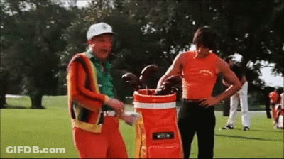 Two Men On Golf Course One Holding Golf Bag GIF