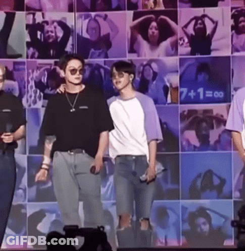 Two Men On Stage In Front Of Picture Wall GIF