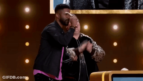 Two Men On Stage With Arms Outstretched One Wearing Glasses GIF