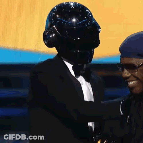 Two Men One In Black Helmet And Tuxedo GIF