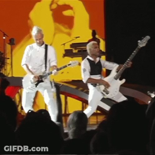 Two Men Playing Guitars On Stage GIF