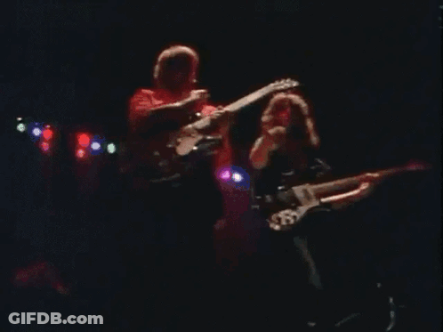 Two Men Playing Guitars On Stage With 'A' Shirt GIF