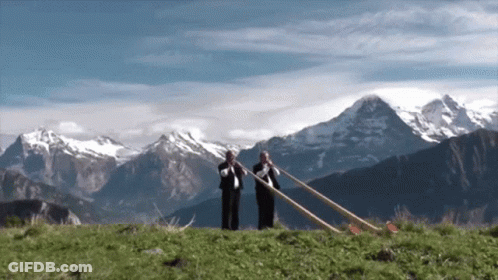 Two Men Playing Horns In Front Of Mountain Range GIF