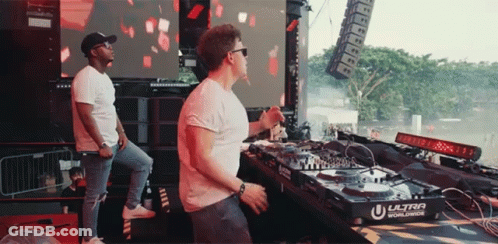 Two Men Playing Music In Front Of Ultra Worldwide Machine GIF