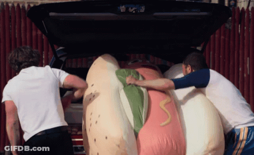 Two Men Pushing Giant Hot Dog In Car GIF