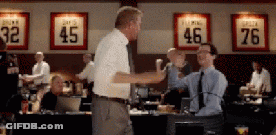 Two Men Shake Hands In Front Of A Wall With Jerseys For Davis And Fleming On It GIF