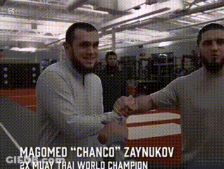 Two Men Shaking Hands In A Gym With The Words Magomed " Chanco " Zaynukov On The Bottom GIF
