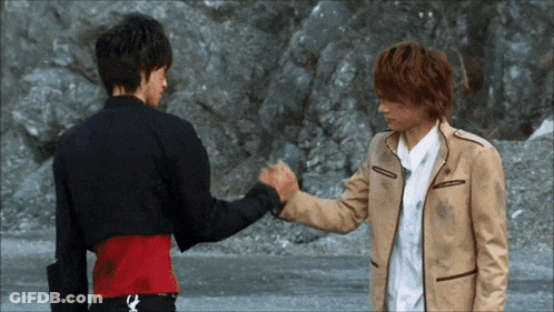 Two Men Shaking Hands In Front Of Rocky Cliff GIF