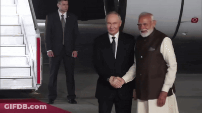 Two Men Shaking Hands On Red Carpet Near Plane GIF