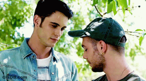Two Men Side By Side, One In Green Hat GIF