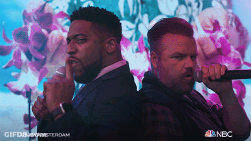 Two Men Singing In Front Of Floral Background With NBC Logo GIF