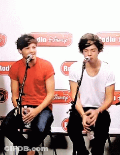 Two Men Singing Into Microphones In Front Of A Wall That Says Radio GIF