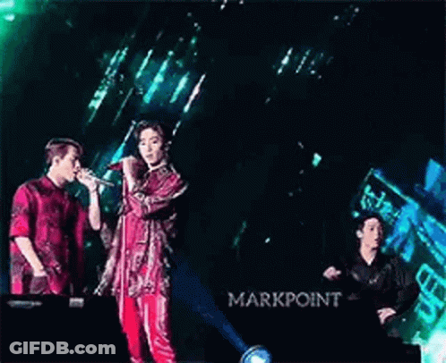 Two Men Singing Into Microphones On Stage GIF