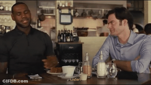 Two Men Sit At A Table In A Restaurant And One Of Them Says " Listen " GIF