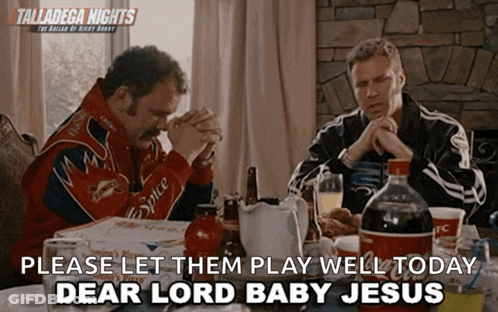Two Men Sit At A Table With A Sign That Says Talladega Nights GIF