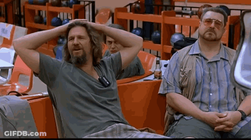 Two Men Sit In A Bowling Alley With Their Hands On Their Head GIF