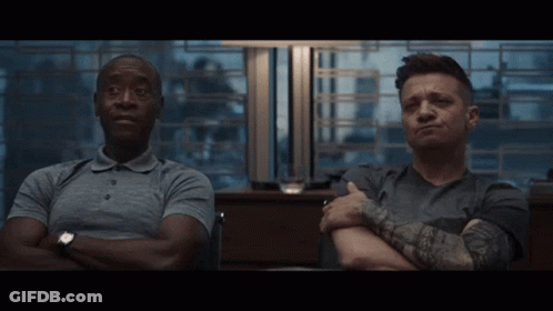 Two Men Sit With Their Arms Crossed And One Has A Tattoo On His Arm GIF